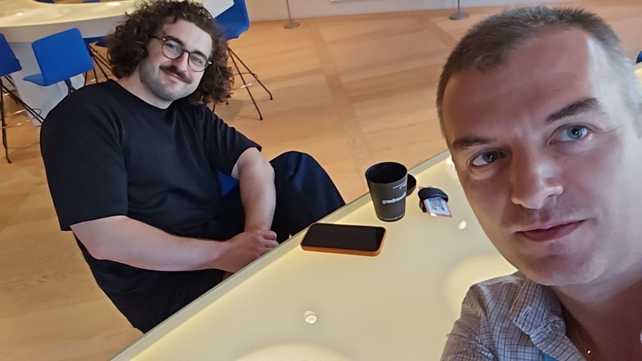 Two people sharing a friendly moment inside a bright building interior